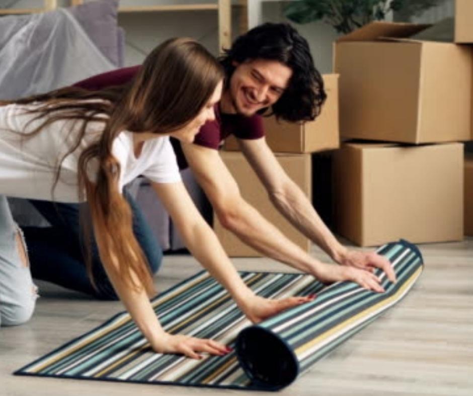 Couple rolling out a carpet together at their new home. 