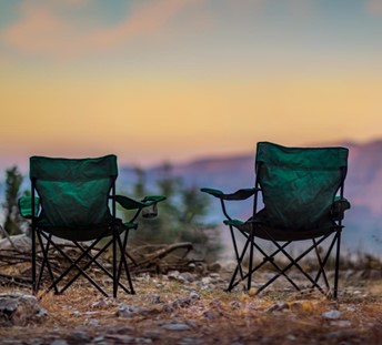 Two green chairs setup at a campsite. 