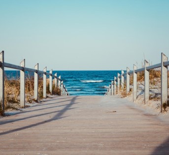 A wooden pier leading down to a sandy beach and blue water. 